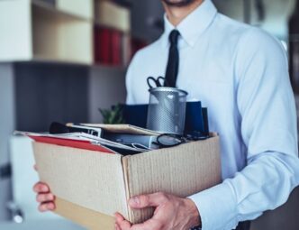 man in shirt and tie carrying a box after clearing out his desk