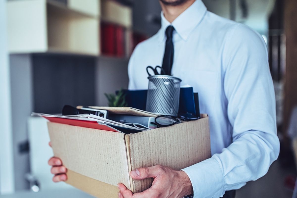 man in shirt and tie carrying a box after clearing out his desk