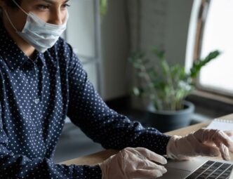 woman wearing gloves and mask and working at computer