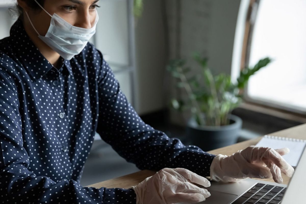 woman wearing gloves and mask and working at computer